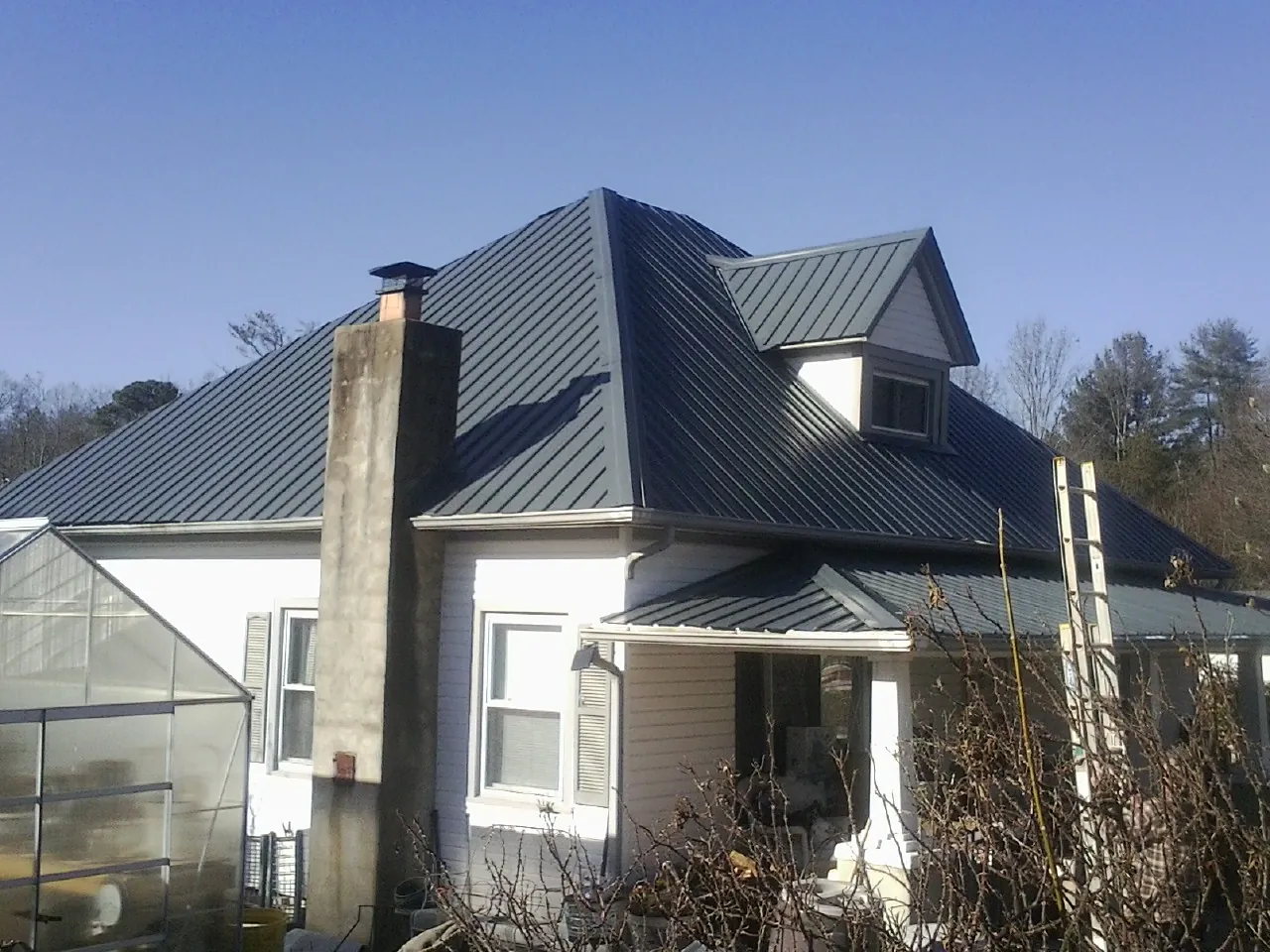 Dark blue standing seam metal roof on a white farmhouse with dormer — Slate & Tile Roof Repair by Roofing Brothers in Van