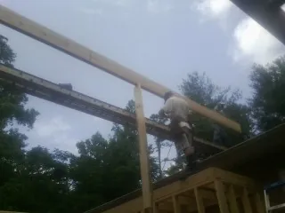 Carpenter setting a ridge beam over a new addition frame — Ice Dam Removal by Roofing Brothers in Van