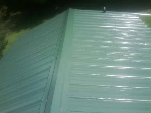 New green metal panels meeting at the ridge of a roof — Flat Roof Repair work by our crew in Van