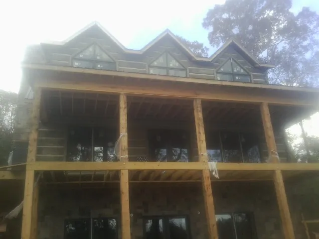 Dormers and porch framing on a large log home under construction — Roof Coating work by our crew in Van