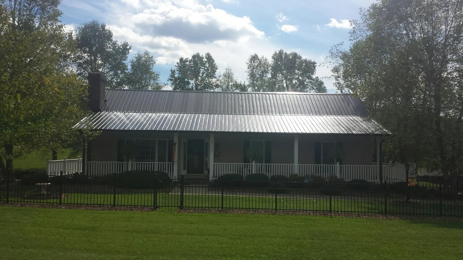 Gray metal roof on a brick ranch with a full width front porch — Gutter Guard Installation work by our crew in Van