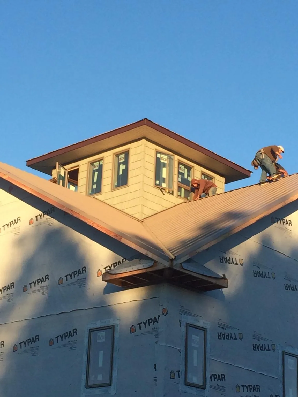 Roofers working around a rooftop cupola on a new metal roof at sunset — Roof Waterproofing in Van by Roofing Brothers